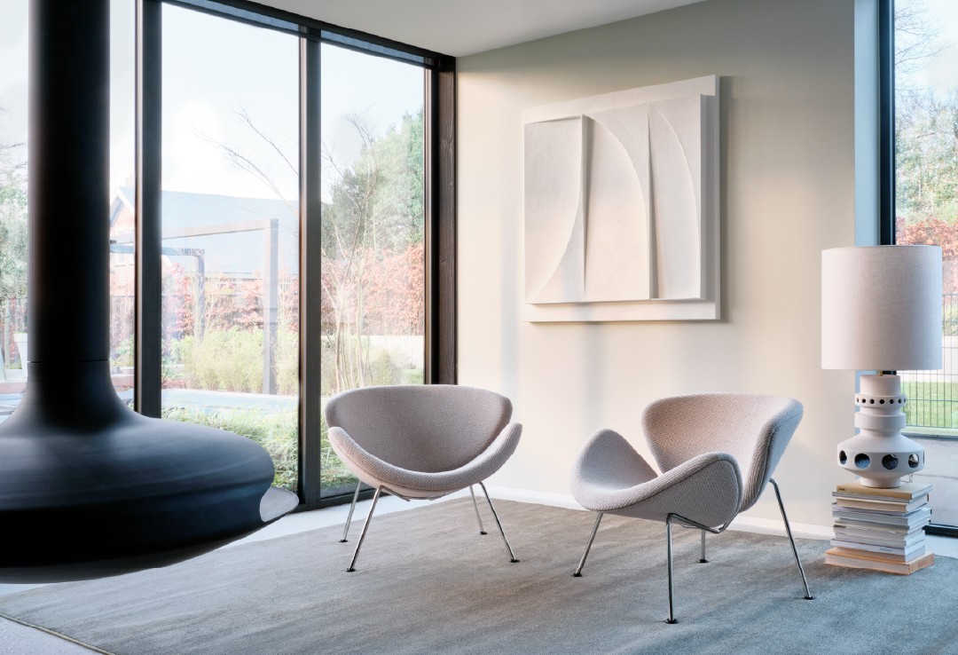 Twee lichtgrijze Artifort Orange Slice fauteuils in een moderne lounge met abstracte wandkunst en hangende haard.