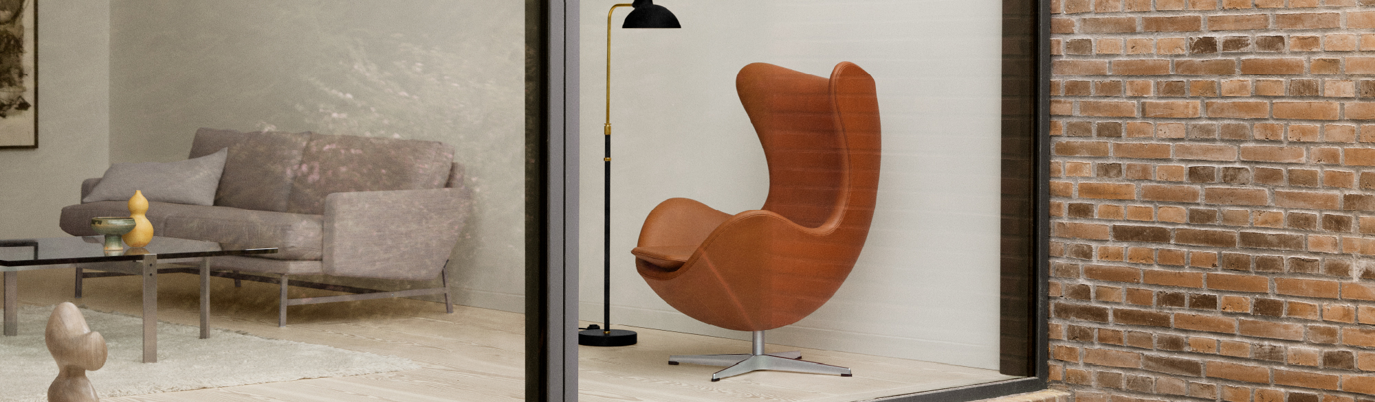 Oranje-bruin leren Egg Chair met metalen draaivoet, zwarte vloerlamp met gouden accent, zicht op moderne woonkamer met grijze bank en glazen tafel.