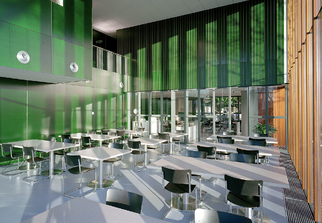 Thonet S43 stoelen met zwart houten zitting en verchroomd buisframe in ruime cafetaria met groene wanden en hoge ramen &ndash; Van Til Interieur.